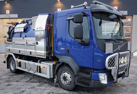 en blå lastebil med diverse utstyr og rør på toppen og baksiden som står fremfor en lagerbygning